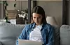 Young woman sit on sofa using laptop gadget