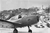 Magne Espeland i cockpiten etter landing på isen utanfor Saudasjøen, kanskje i 1957-58? Huset til banksjef Øverland i bakgrunnen (på venstre sida av innkøyringa til Saua Gard). Foto lånt av Helmut Thiem.