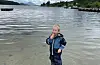 Norsk sommar. Eivind, fire år, kosar seg med is på stranda.